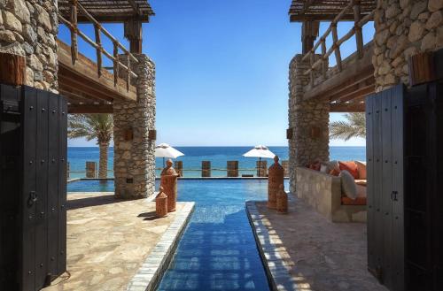 a resort with a pool and the ocean in the background at Six Senses Zighy Bay in Dibba