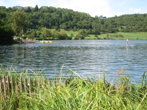 a person on a paddle board on a lake at Ferienwohnungen Haus Hinneres in Schalkenmehren