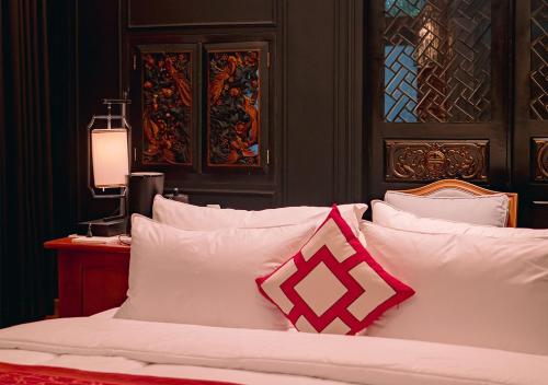 a bedroom with a bed with white pillows at House of Tugu, Old Town Jakarta in Jakarta