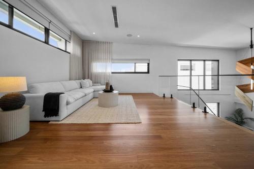 a living room with a white couch and wooden floors at Blvd Dream in Shellharbour