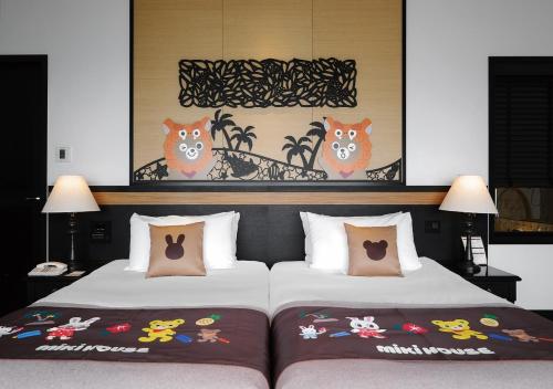 two beds in a hotel room with paintings on the wall at Hotel Monterey Okinawa Spa & Resort in Onna