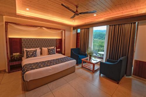 a bedroom with a bed and two chairs and a balcony at Nazaara - A Luxe Retreat in Manāli