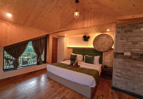 a bedroom with a bed and a large window at Nazaara - A Luxe Retreat in Manāli