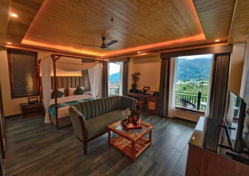 a living room with a couch and a bed and a table at Nazaara - A Luxe Retreat in Manāli