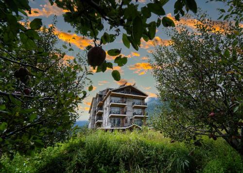 a building in the middle of a field with trees at Nazaara - A Luxe Retreat in Manāli
