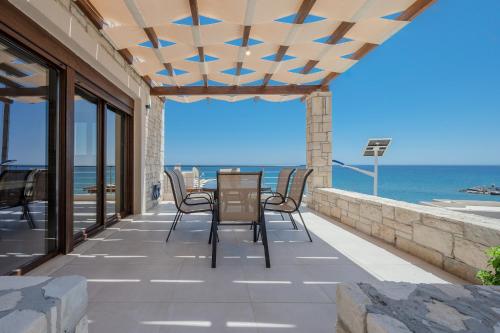 a patio with a table and chairs and the ocean at Petrina 3 villa by the sea in Keratokampos