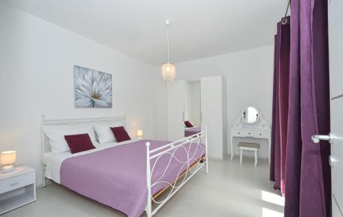 ein weißes Schlafzimmer mit einem lila Bett und einem Schreibtisch in der Unterkunft House Pazanin in Vinišće