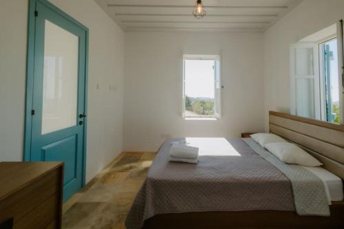 a bedroom with a bed with a blue door and a window at Dipaton House in Vasa 2 in Vasa Kilaniou