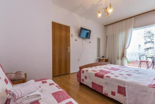 a bedroom with two beds and a tv and a window at Apartments and Rooms Happiness in Tučepi