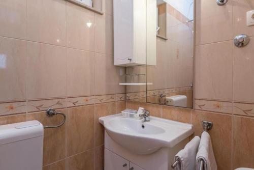 a bathroom with a sink and a toilet and a mirror at Apartments and Rooms Happiness in Tučepi