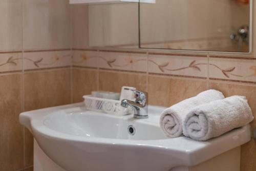 a bathroom with a sink and a mirror and towels at Apartments and Rooms Happiness in Tučepi