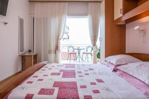a bedroom with a bed and a window with a table at Apartments and Rooms Happiness in Tučepi