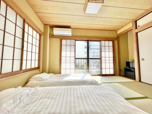 a bedroom with two beds in a room with windows at Toko inn Japanese-style room popularity in Tokyo