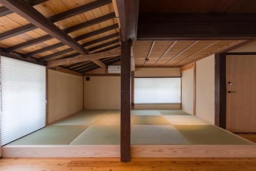 an empty room with windows and a wooden ceiling at FARMSTAY miyuki-street "Hotaru" in Kugumiya