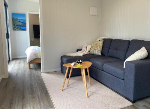 Bethells BeachにあるTe Henga Hideawayの青いソファとテーブルのあるリビングルーム