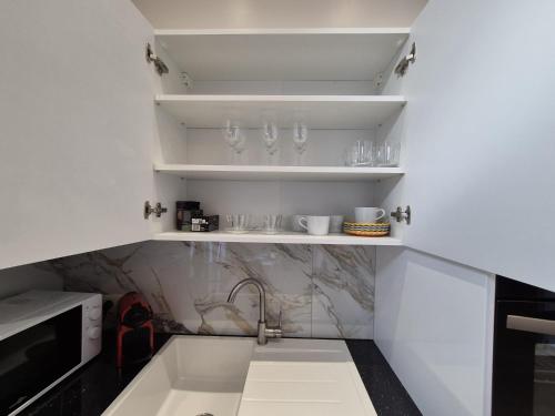 una cocina con fregadero y estanterías con gafas en Elegant apartment in center of Brussels, en Bruselas