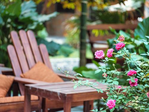 a wooden table and two chairs and pink flowers at Cozy Beer Garden Homestay in Ninh Binh