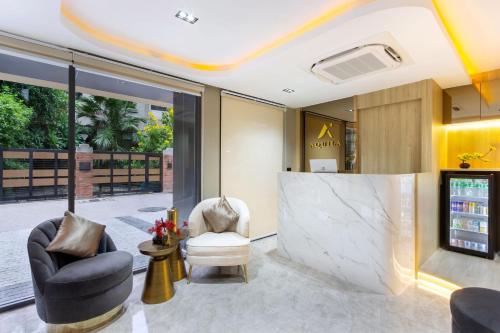 a lobby with two chairs and a marble wall at Aquila Hotel Bangkok in Bangkok