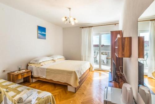 a bedroom with two beds and a flat screen tv at Apartments and Rooms Happiness in Tučepi