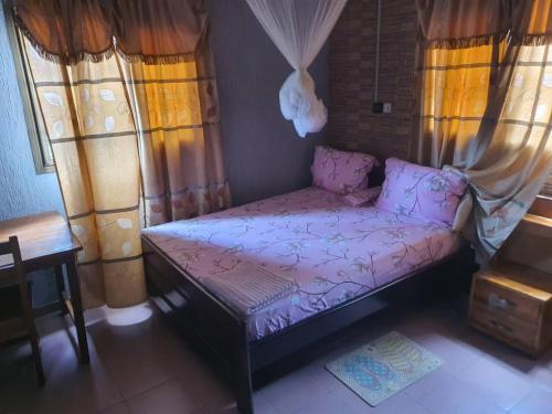 a small bed in a room with windows at RÉSIDENCE VICTORIA in Lomé