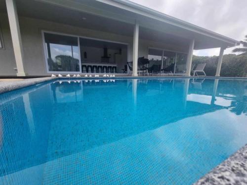 a large blue swimming pool in front of a house at Te Aro Villa in Muri 1 &2 in Rarotonga