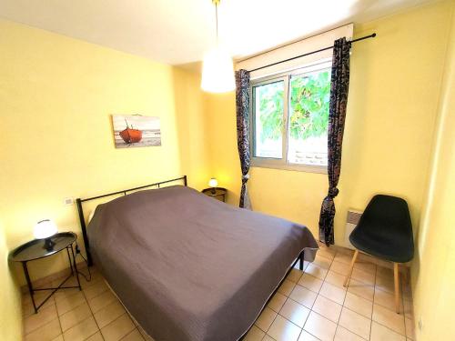 une chambre avec un lit, une fenêtre et une chaise dans l'établissement soleil catalan 150m mer ok chéques vacances animaux 1ere étage 4pers wifi parking, à Saint-Cyprien