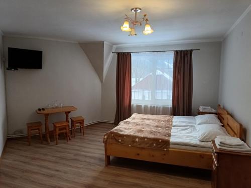 a bedroom with a bed and a table and a window at Сільська Садиба in Kvasy