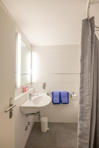 a white bathroom with a sink and a mirror at Hotel Chesa Spuondas in St. Moritz