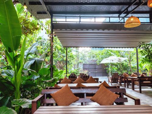 a restaurant with wooden tables and chairs and plants at Cozy Beer Garden Homestay in Ninh Binh