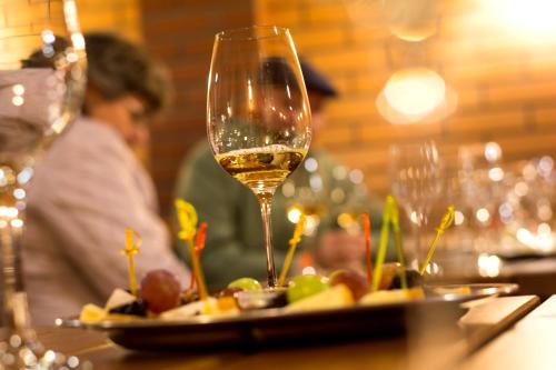 a glass of wine on a table with a plate of food at Sástó Hotel in Matrafured