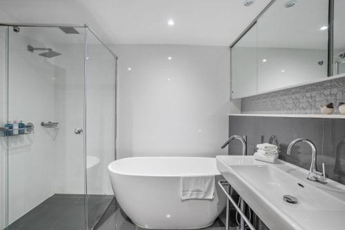 un bagno con vasca, lavandino e doccia di Byron Marvel - Luxury Byron Bay Penthouse Holiday Rental with Balcony, 4 Bedrooms, Sleeps 10 a Byron Bay