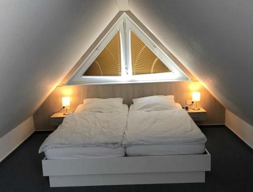 a bedroom with a bed with a window and two lamps at Haus Petra in Borkum
