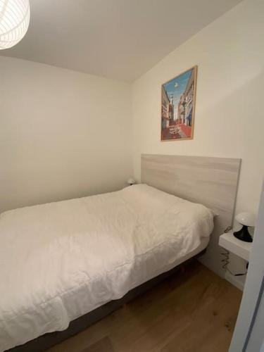 - une chambre avec un lit blanc et une photo sur le mur dans l'établissement Park avenue, 6 pers, plein centre, parking et linge inclus, à Le Touquet-Paris-Plage