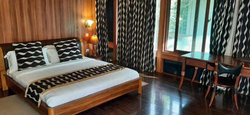 a bedroom with a bed and a desk next to a window at AA Lodge Maasai Mara in Talek