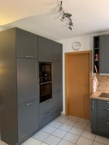 a kitchen with gray cabinets and a clock on the wall at Haus Petra in Borkum