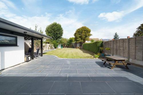 a patio with a wooden bench and a fence at Stunning Family Bungalow With Private Parking in Dagenham