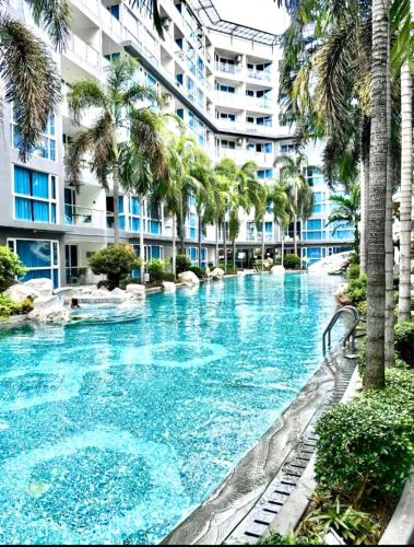 a swimming pool with palm trees in front of a building at Centara Pattaya Apartment in Pattaya