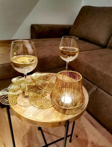 two glasses of wine on a table in front of a couch at Ferienwohnung Thomas Müntzer in Mühlhausen