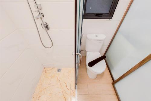 a small bathroom with a toilet and a shower at Spacious and Comfortable 2BR at Sky House BSD Apartment By Travelio in Tangerang