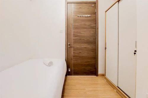 a bedroom with a bed and a wooden door at Spacious and Comfortable 2BR at Sky House BSD Apartment By Travelio in Tangerang