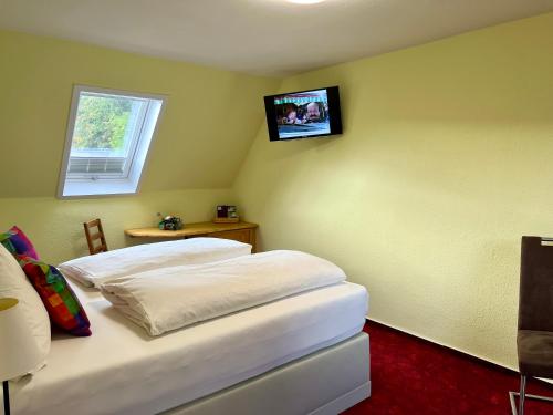 a bedroom with two beds and a tv on the wall at Berghotel Talblick in Holzhau