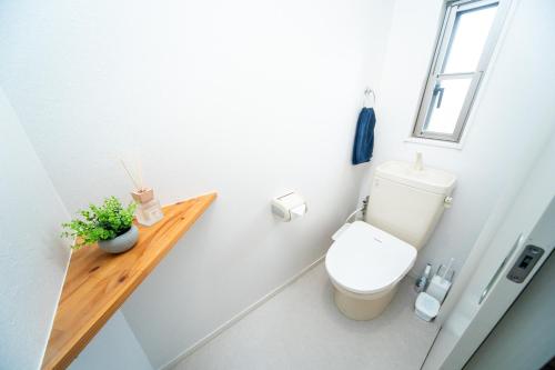 a bathroom with a toilet and a wooden shelf at Miraie Yokkaichi Hinaganishi in Nishi-hino