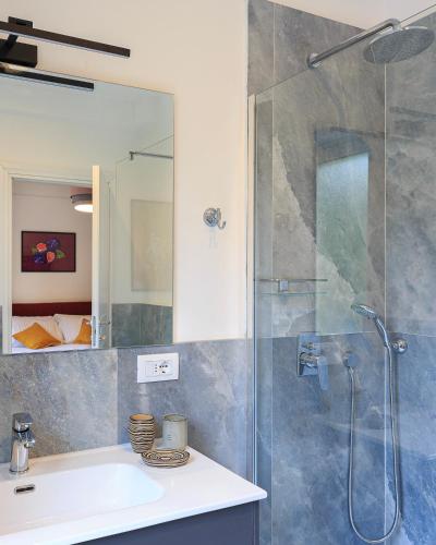 a bathroom with a shower with a sink and a mirror at Sense Rooms in Baveno