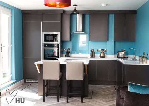 a kitchen with black cabinets and blue walls at Sky Marina Suite Penthouse in Hull
