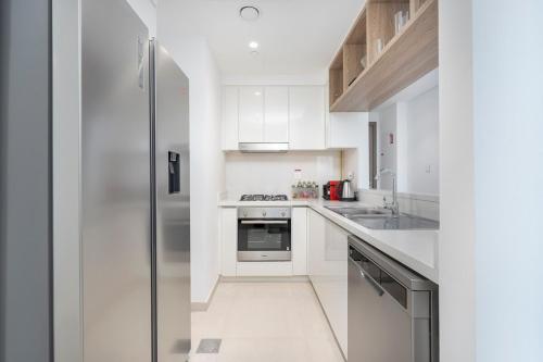 a kitchen with white cabinets and a stainless steel refrigerator at Free housekeeping visits during your stay - StayShort - Beautiful 2-BR Flat in Downtown Luxury City Living at Its Best in Dubai