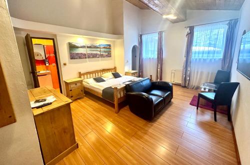 a bedroom with a bed and a couch and a chair at Hotel Lesana in Špindlerův Mlýn