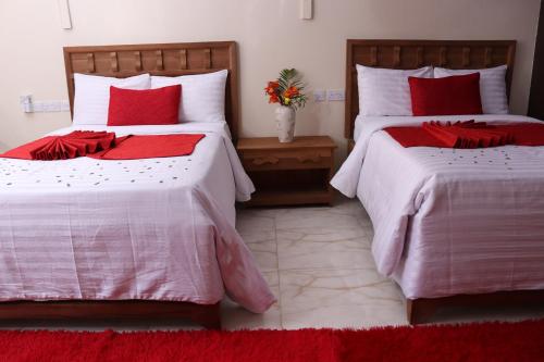 two beds in a bedroom with red and white sheets at White Peacock Resort Mtwapa in Mombasa