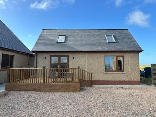 a house with a wooden deck in front of it at Flat in Eoropie, Ness, Isle of Lewis in Port of Ness