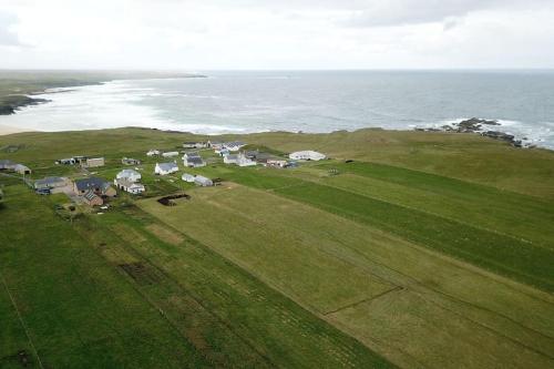 an aerial view of a field with houses and the ocean at Flat in Eoropie, Ness, Isle of Lewis in Port of Ness