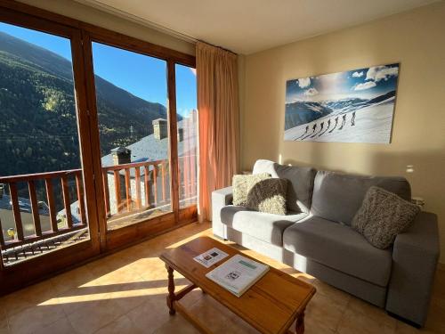 a living room with a couch and a large window at Apartaments Font del Poble in Ransol